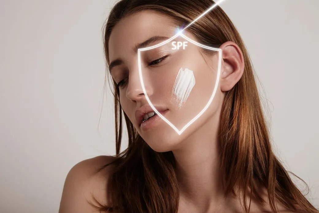 Woman applying SPF sunscreen with a protective shield graphic on her face, highlighting sun protection for maintaining Endolift results.